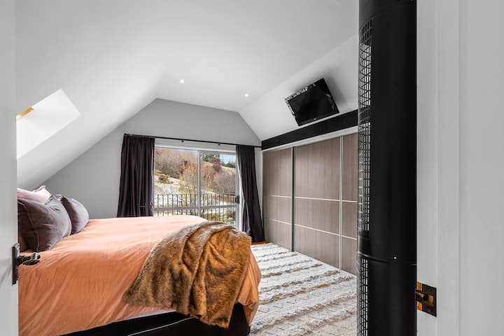De hoofdslaapkamer is boven weggestopt. Het heeft een eigen badkamer en een eigen balkon om het beste uitzicht op het platteland en de bergen van Queenstown te zien