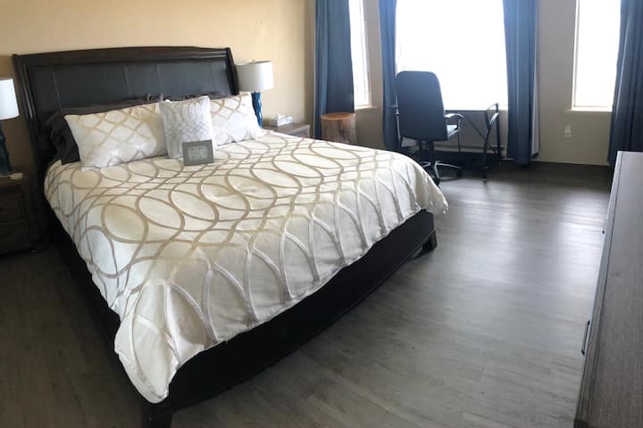 The master bedroom features a large, comfortable king bed with ensuite bathroom, closet, and walnut dresser. Wall outlets by the bed feature USB ports for easy charging of devices. The bedroom even includes a workspace that overlooks the water.