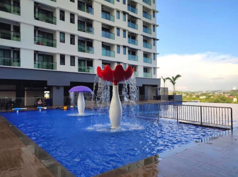 A resort-style swimming pool is featured, complete with playful water fountains designed as vibrant flowers. Spacious surrounding areas provide room for relaxation, while palm trees are visible in the distance, complementing the scenic view of the neighborhood.