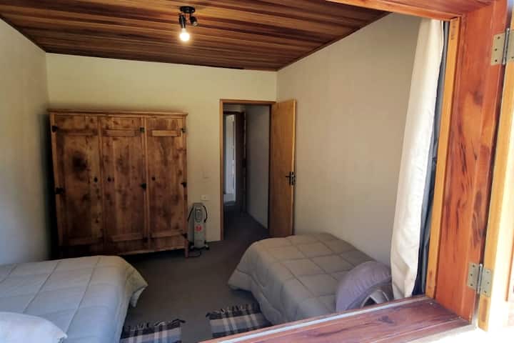 Habitación 2 vista desde el exterior, con dos camas separadas. En cada habitación hay dos almohadas, dos edredones y una guardada para cada cama, todo de buena calidad.