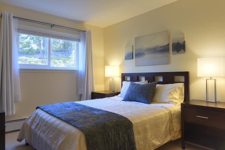 Bedroom with Queen Size Bed, 2 Night Stands, Dresser and Closet. Window with blinds and blackout curtains.
