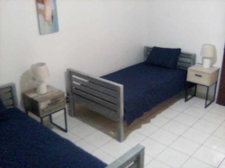 4e slaapkamer met 2 eenpersoonsbedden, individuele nachtkastjes met lampen en stoelen.  Ook voorzien van zowel plafond- als voetstukventilatoren.