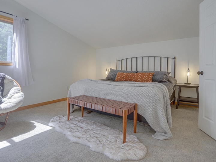 Chambre principale à l'étage avec lit King Size, sièges confortables et télévision.