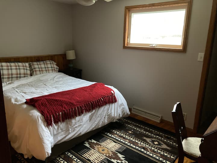 Chumba cha kulala cha pembeni kilicho na kitanda aina ya queen na sehemu ya kufanyia kazi iliyo na dawati na kabati kubwa la kiti 