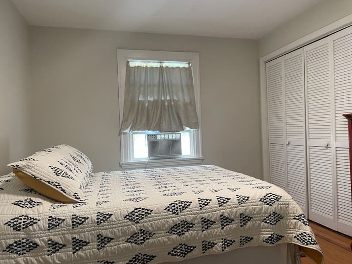 غرفة نوم في الطابق السفلي مع مرتبة جديدة بحجم كوين. 