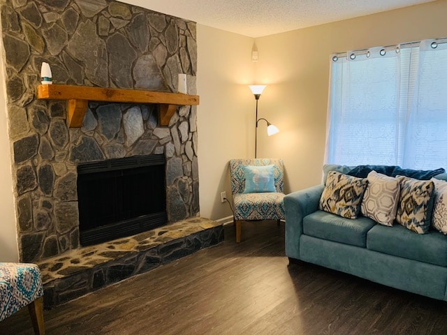 A cozy living room features a stone fireplace with a wooden mantel, complemented by two patterned chairs. A light blue sofa adorned with decorative pillows invites relaxation. Natural light filters through sheer curtains, illuminating the space.