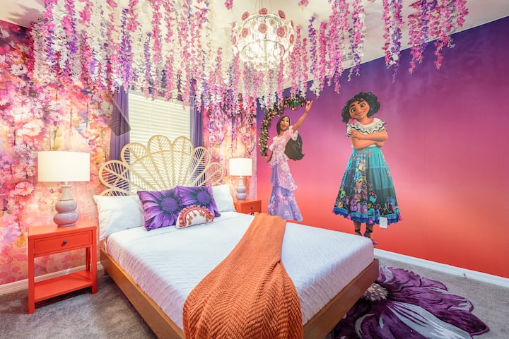 Dormitorio temático encantador inspirado en una familia mágica, con arte mural vibrante, una impresionante lámpara de araña, decoración de techo floral y ropa de cama acogedora. Un refugio caprichoso perfecto para despertar la imaginación y crear recuerdos inolvidables