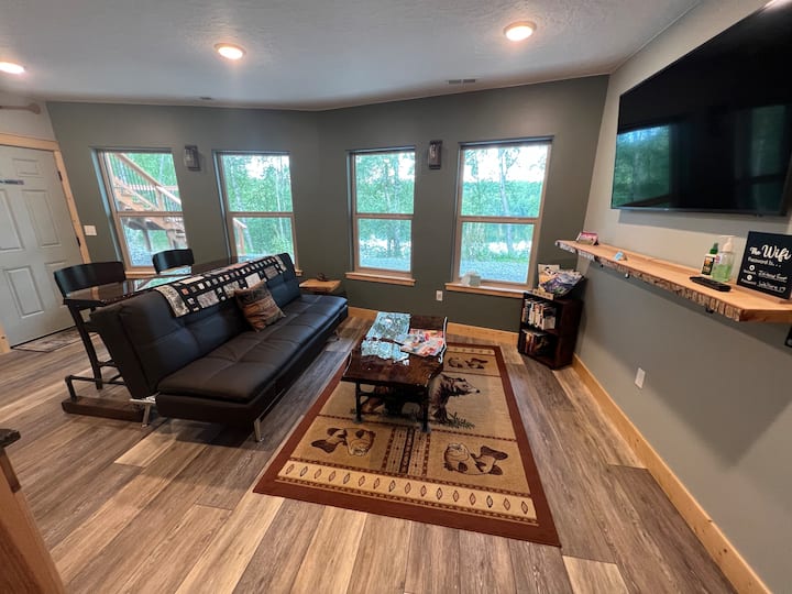 Área común con televisión, cocina pequeña, sofá, mesa de sofá y vista al lago.