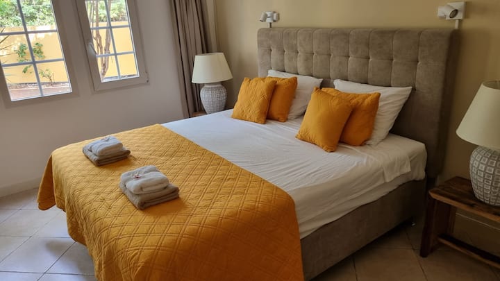 Eerste slaapkamer met kingsize boxspring. Airco, plafondventilator & TV.