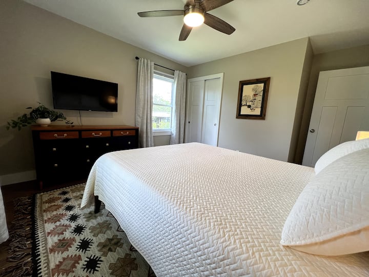 Queen bedroom with 40 in Smart TV. Bedside tables have lamps with USB plugs to charge your electronics and a sound machine.