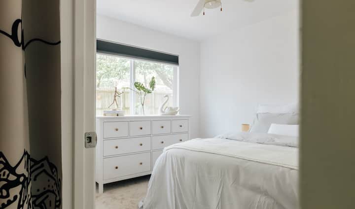 חדר שינה 2 כולל מיטה זוגית, מזרן בינוני חדש, מצעים נוחים, שידת איקאה יפה וחלון גדול עם נוף למזרקה.