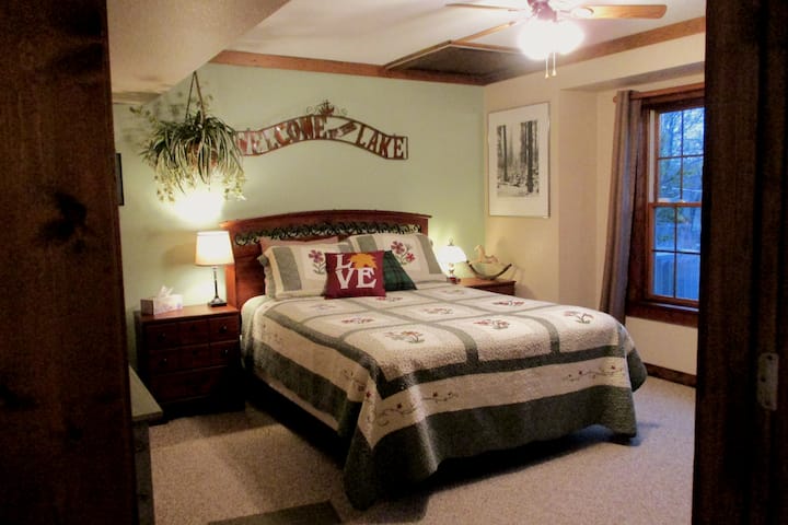 Private bedroom with door and Queen size Bed, night stands, dresser, work space and a view to the backyard.