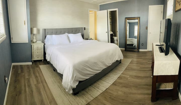 Cama king en suite principal con vistas al lago y TV.