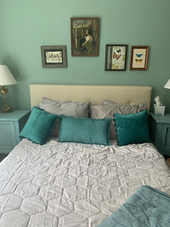 مرتبة جديدة تمامًا في غرفة نوم كبيرة بسرير بحجم كبير وأريكة وتلفزيون ومحطة عمل.