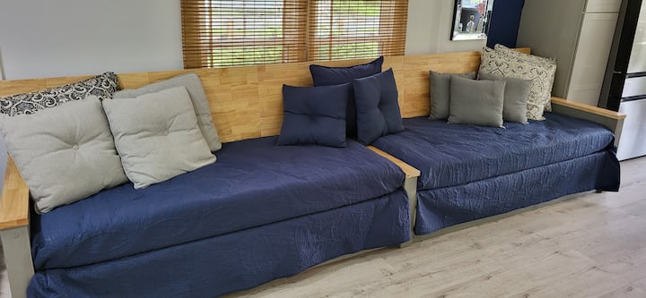¡salón versátil y refugio para dormir! Nuestro sofá extragrande personalizado de 13 pies es perfecto para descansar durante el día mientras disfrutas de las pintorescas vistas al río a través de las puertas dobles. Por la noche, esta pieza se transforma en cuatro camas individuales, proporcionando un amplio espacio para dormir