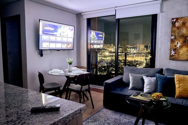 Imaginez arriver dans cet appartement confortable après une journée d'exploration de la ville. Vous êtes accueilli par un espace moderne et chaleureux qui vous invite à vous détendre. La baie vitrée vous offre une vue panoramique imprenable sur la ville éclairée, créant une expérience unique
