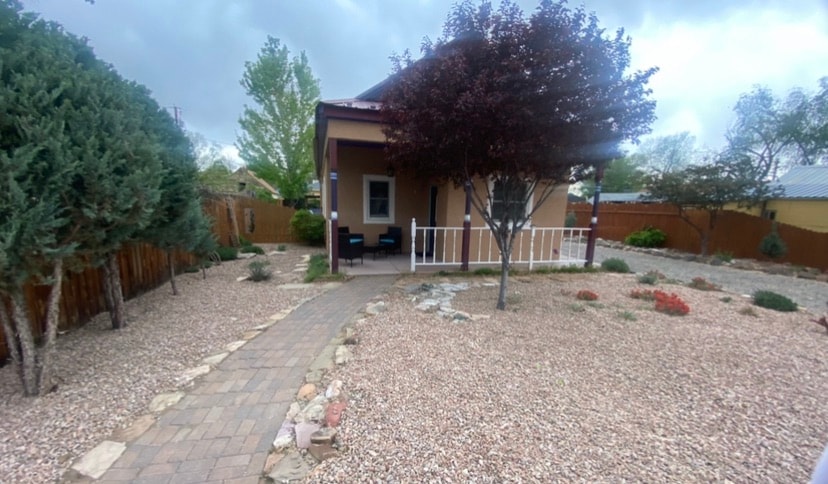 A well-maintained front yard is showcased, featuring a stone pathway leading to a welcoming entrance. Lush shrubs and a flowering tree provide greenery amidst the gravel landscaping. The home’s porch area has seating arrangements, creating a cozy outdoor ambiance.