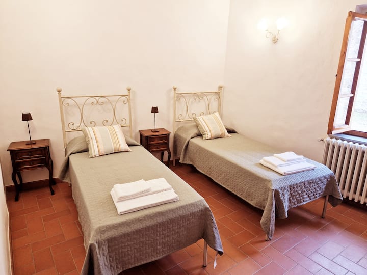 غرفة تضم سريرين مفردين وكرسي بذراعين/سرير مفرد