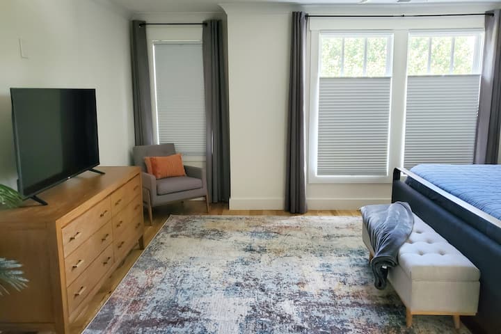 Chumba cha kulala cha msingi chenye nafasi kubwa kina vivuli na mapazia ya kuzima