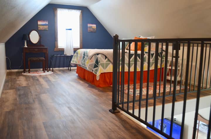 El dormitorio loft tiene una cama tamaño queen, tocador y ventana orientada al oeste con hermosas vistas a las montañas Big Belt.