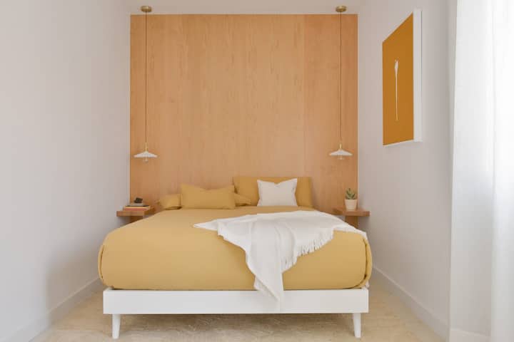 Dormitorio doble con panel de madera y obras de arte originales.