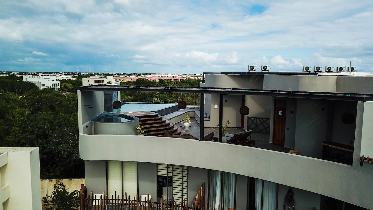 An expansive view features a modern roof terrace with a private infinity pool. The space is surrounded by lush greenery and incorporates outdoor seating areas. The architecture is sleek, with multiple air conditioning units visible on the upper level.