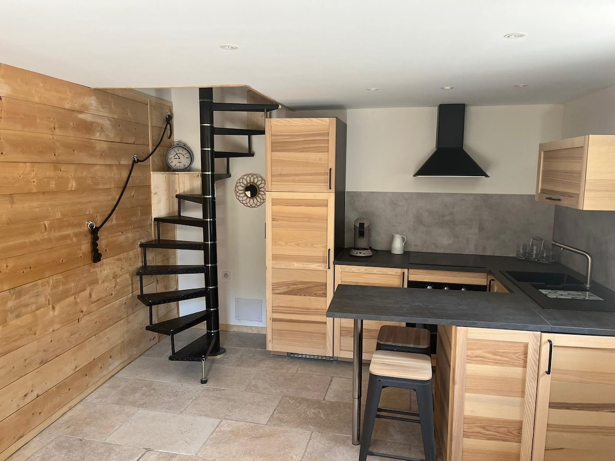 An open kitchen is showcased, featuring wooden cabinetry and sleek gray countertops. A spiral staircase is visible in the corner, adding a unique architectural element. The egg timer and minimalist appliances bring functionality to this inviting space.