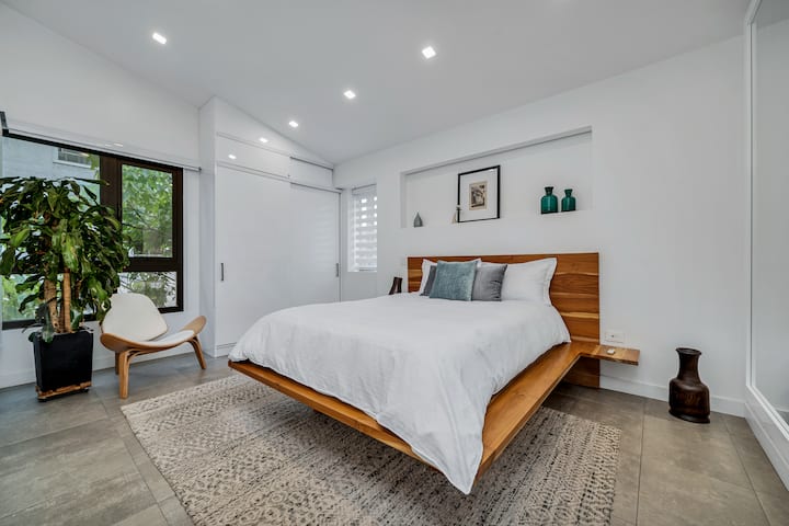 Dhomë gjumi e bollshme me një dizajn të pastër dhe modern. Përmban një kornizë krevati lundruese prej druri, dritare të mëdha dhe dekor plot shije duke krijuar një atmosferë qetësuese.