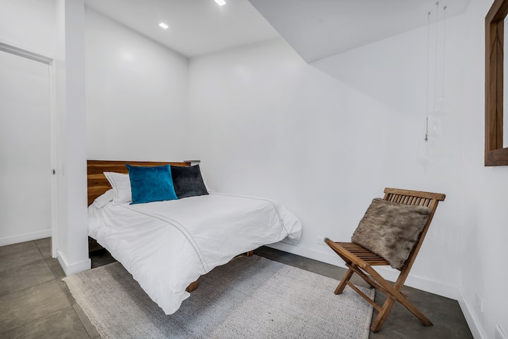 Dhomë gjumi për vizitorët me ndriçim të butë, linja të pastra dhe një krevat të rehatshëm; ideale për një natë të qetë gjumi.