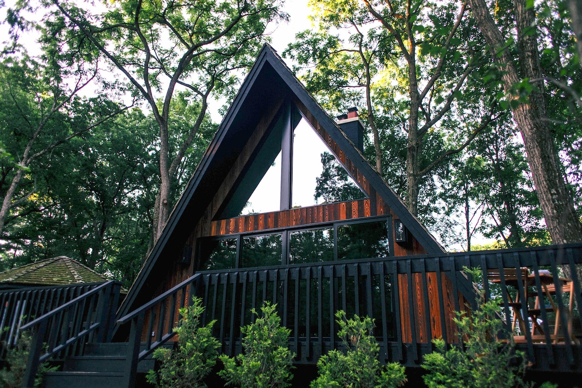 A black a-frame building among trees.