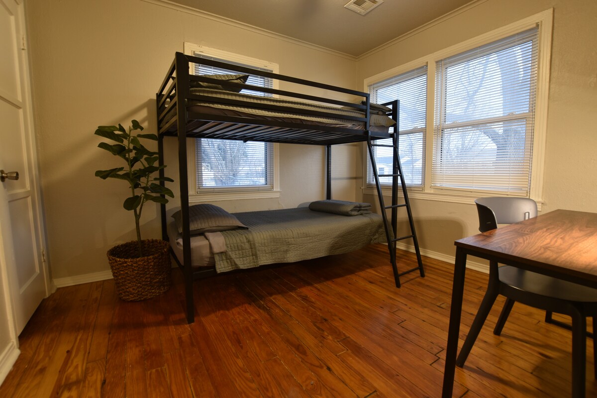 Alojamiento acogedor con una moderna litera de metal, suelos de madera pulida y luz natural brillante.