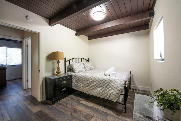 The first bedroom to the right of the living room in the Big house features a Queen Sized bed and TV mounted on the wall.