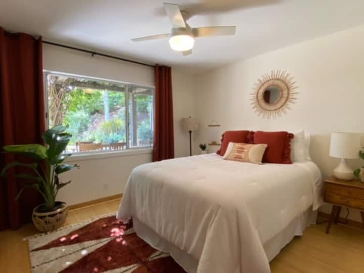 Chumba cha kulala cha ghorofa ya chini 2 na kitanda cha malkia - chumba cha 'Terracota'; dirisha linaloangalia nje ya eneo la kulia chakula