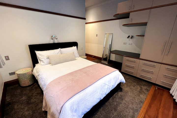 EL DORMITORIO DE INVITADOS 3 cuenta con un baño privado, ropa de cama de calidad, una alfombra de felpa, un armario y un escritorio/tocador. Las puertas dobles conducen a una terraza cubierta y a vistas sobre la terraza trasera (juego de ajedrez gigante, mesa de comedor y anillo de baloncesto).