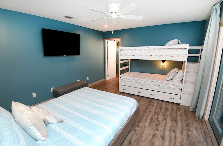 This bedroom has a twin over twin bunkbed with twin trundle and queen bed. The room has an en suite full bathroom, 55 inch tv, closet and French doors to the adjoining wrap around patio. 
