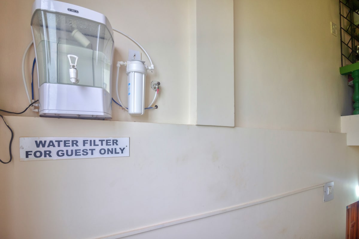 A water filter is mounted on the wall, specifically designated for guest use. A sign below the filter clearly states 'WATER FILTER FOR GUEST ONLY.' The wall has a neutral color, providing a clean and functional appearance.