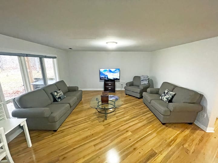 Welcome to the cozy basement living room, a perfect spot for relaxation and entertainment. This spacious area features comfortable seating, a large TV for movie nights, and beautiful hardwood floors that add warmth to the room. The large windows brin
