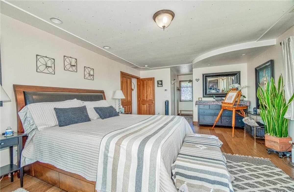 Главна спална соба на горниот кат со брачен кревет (широк 150-179 см), сопствена бања и лизгачка стаклена врата со пристап до балкон.