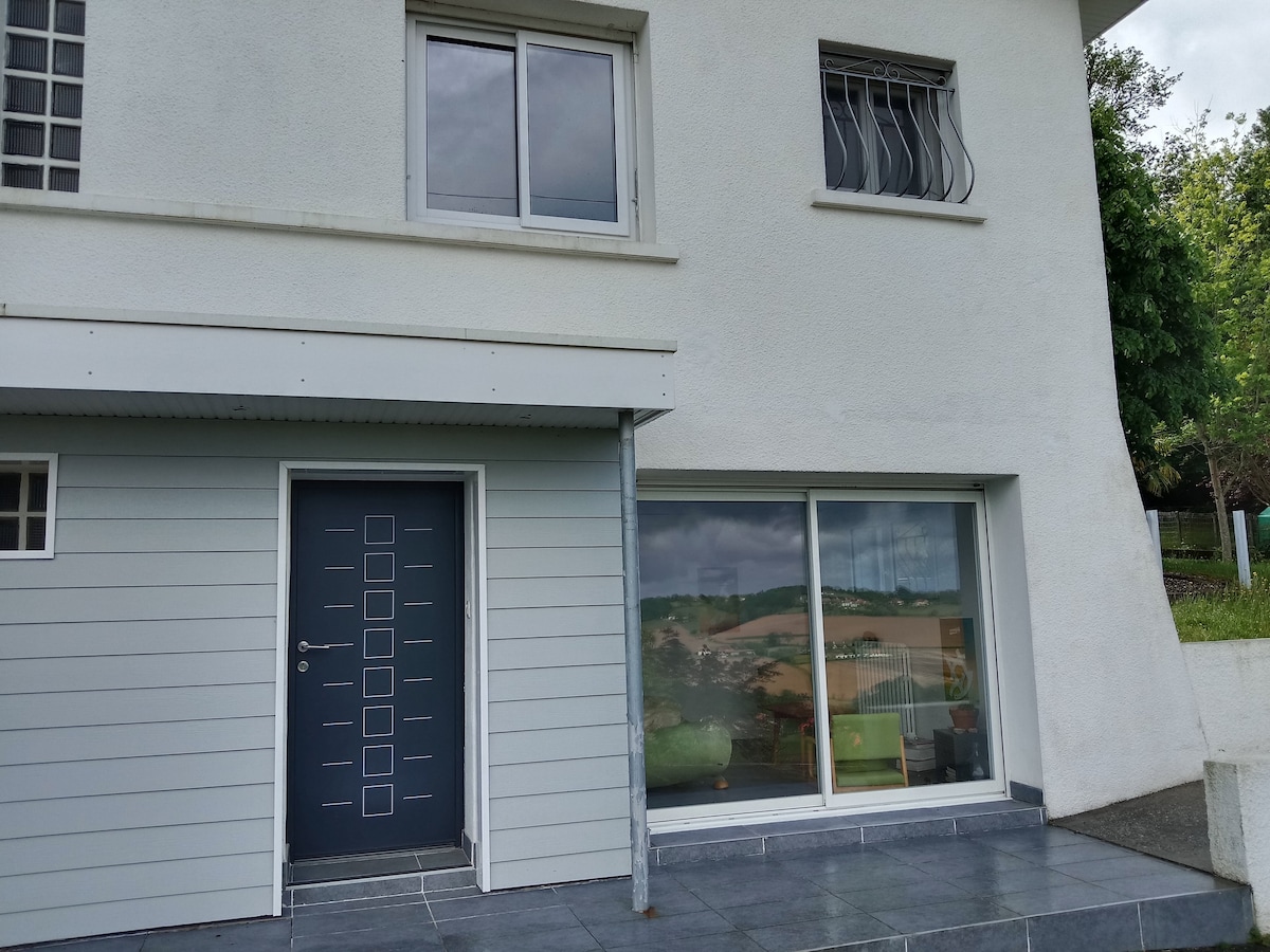 The exterior of the home features a modern front door with a geometric design. Large windows provide a view into the interior space, allowing natural light to enter. A covered entryway with tile flooring enhances accessibility.