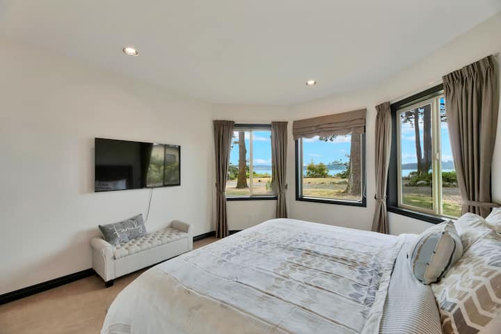 Cama tamaño king con una pared orientada al mar de tres ventanas, que proporciona una vista obstruida.