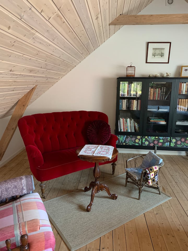 Დასაჯდომი ადგილი დახრილი სახურავის ქვეშ, ტახტითა და სამკითხველო სკამით. Მის გვერდით არის წიგნების კარადა სხვადასხვა ენაზე ლიტერატურით. Რა თქმა უნდა, უმცროსი სტუმრებისთვის საბავშვო ზომის სავარძელი გვაქვს:) იდეალური ადგილია წვიმიან დღეს შიდა ცხოვრებით დასატკბობად!