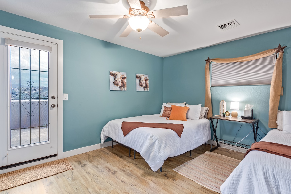 Segundo dormitorio para huéspedes con dos camas tamaño queen y puerta de acceso a la terraza con vistas a la azotea.