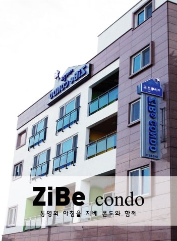 The exterior of ZiBe Condo features a modern, multi-story building with large windows and a prominent sign. The facade is complemented by a mixture of pastel colors, which add a welcoming touch to the atmosphere. The entrance is easily accessible.