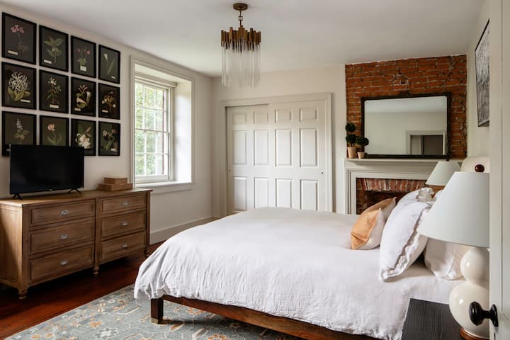 This guest suite is full of style - from the designer chandelier to the gallery wall of botanical prints.  With thoughtful amenities like a SmartTV and dresser, you'll be supremely comfortable in this room!
