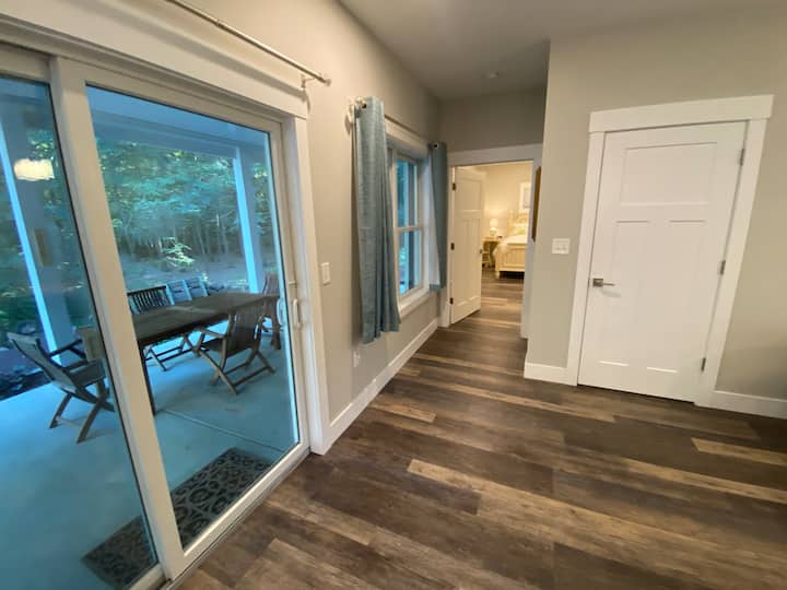 Სამზარეულოს კუნძულის ბოლოში დგას და უკანა პატიოსა და მთავარი საძინებლისკენ იყურება 