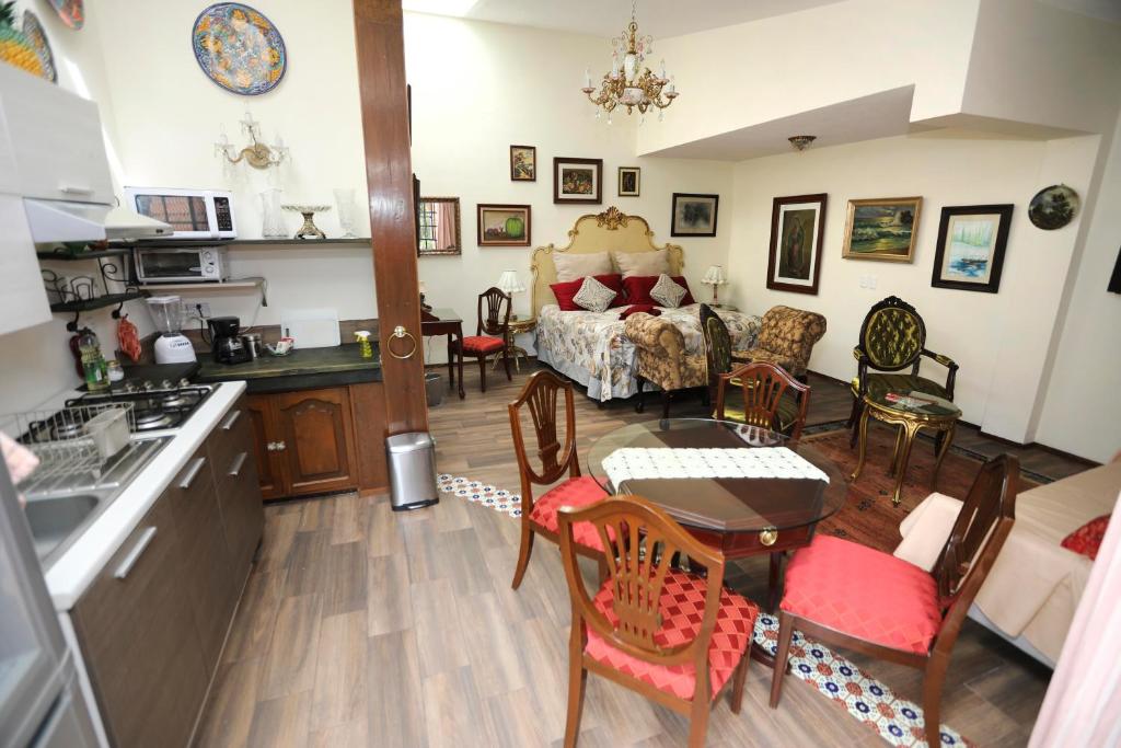 An open concept living space showcases a mixture of vintage and contemporary design elements. A spacious bed is positioned beside a dining area with a wood table and colorful chairs. Decorative artworks adorn the walls, contributing to a gallery-like ambiance.