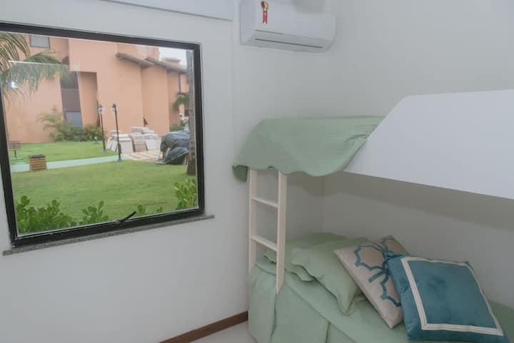 Chambre 4. Vue panoramique sur l'aile centrale de la copropriété, lit superposé avec trois lits simples, penderie une porte, climatisation partagée et télévision