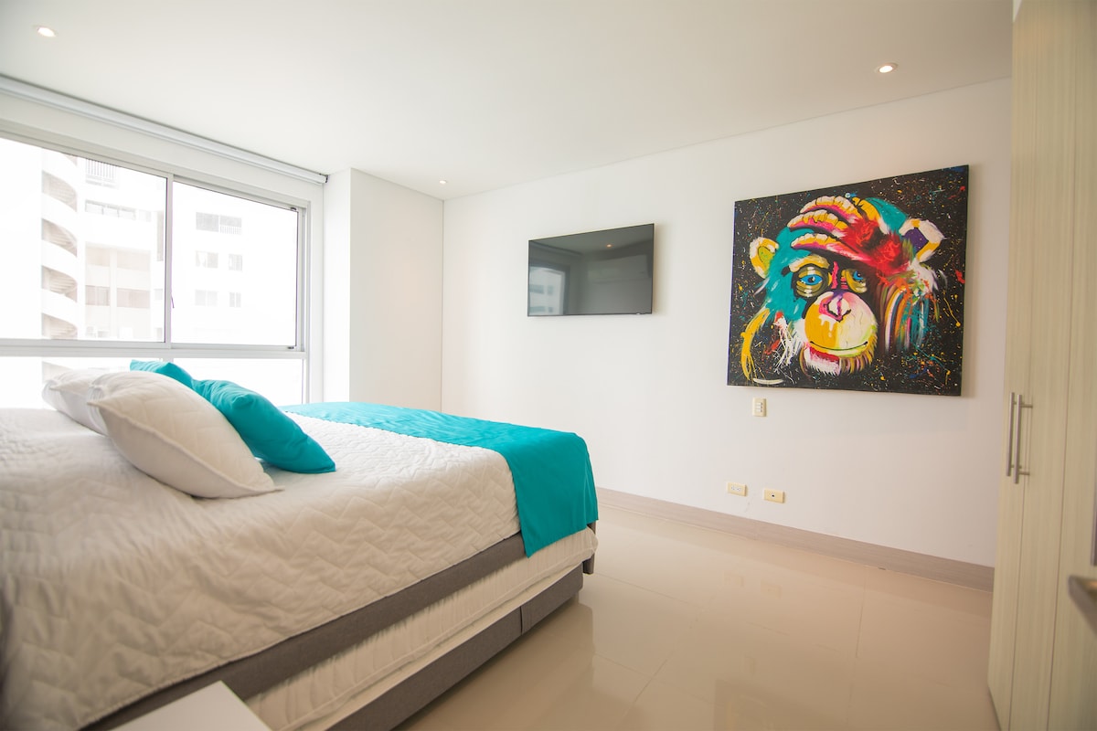 kitanda kikubwa katika chumba cha kulala chenye televisheni mahiri na sanaa. amka na una mwonekano wa bahari na ufukweni kutoka kitandani mwako. Pia kuna maduka ya usb c/a kando ya vitanda.