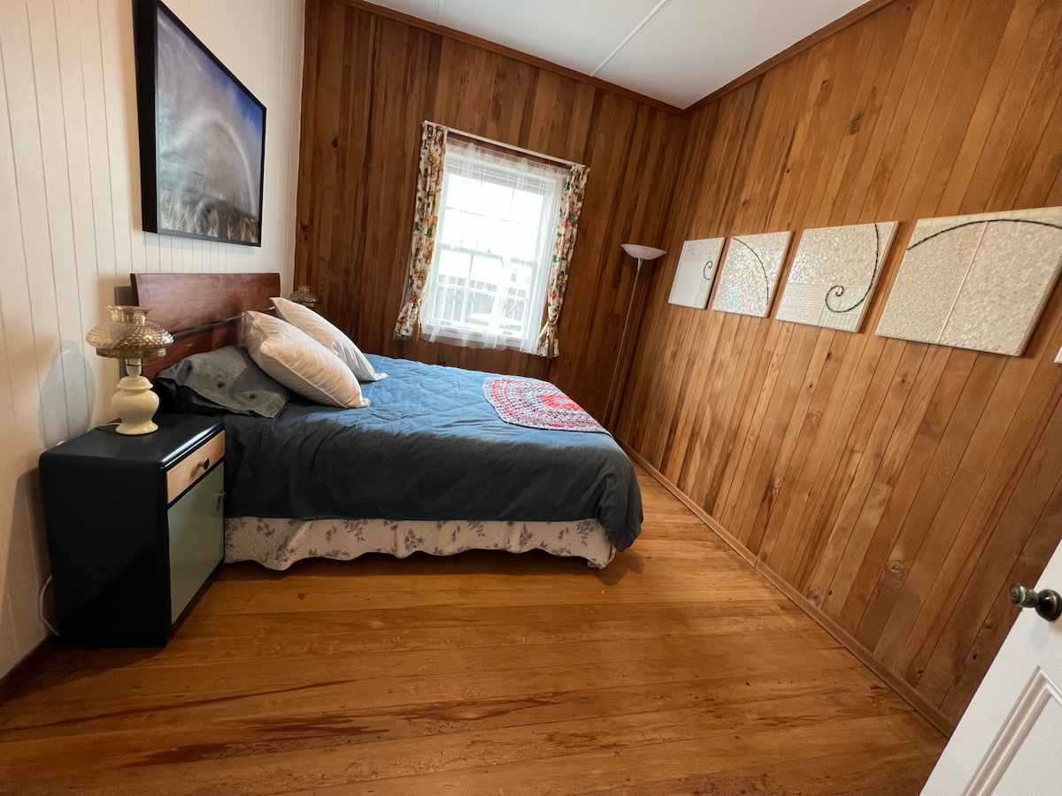 El segundo dormitorio tiene una cama tamaño queen y paneles de rimu.  