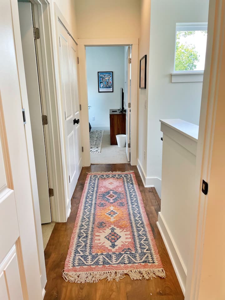 Un couloir décoré d'un joli tapis West Elm relie la salle de bain principale, la buanderie et les deux chambres. 